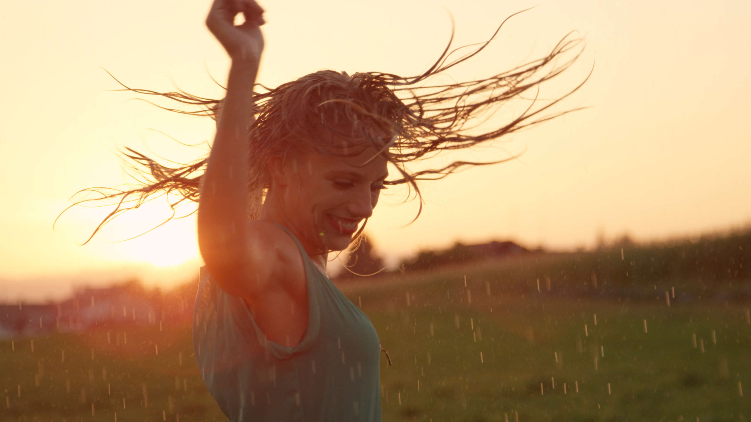 tańcząca na tle zachodzącego słońca kobieta z rozpuszczonymi włosami