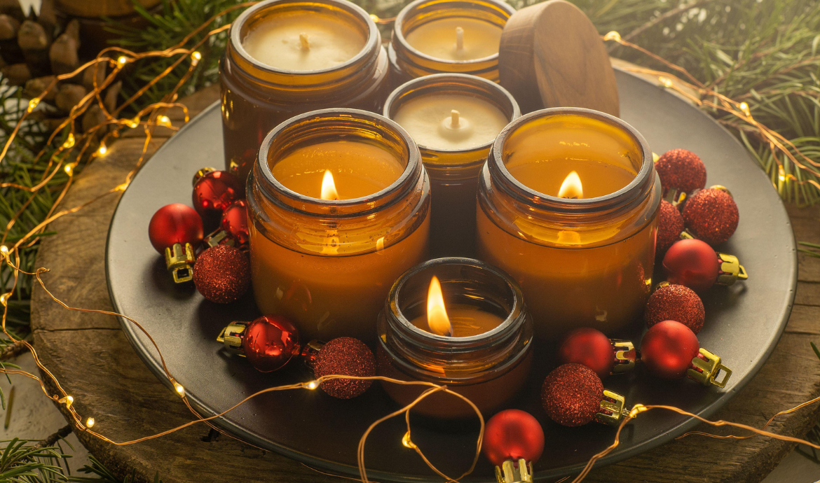Obraz przedstawia dekoracje świąteczne - zapalone świece, łańcuch świetlny i bombki